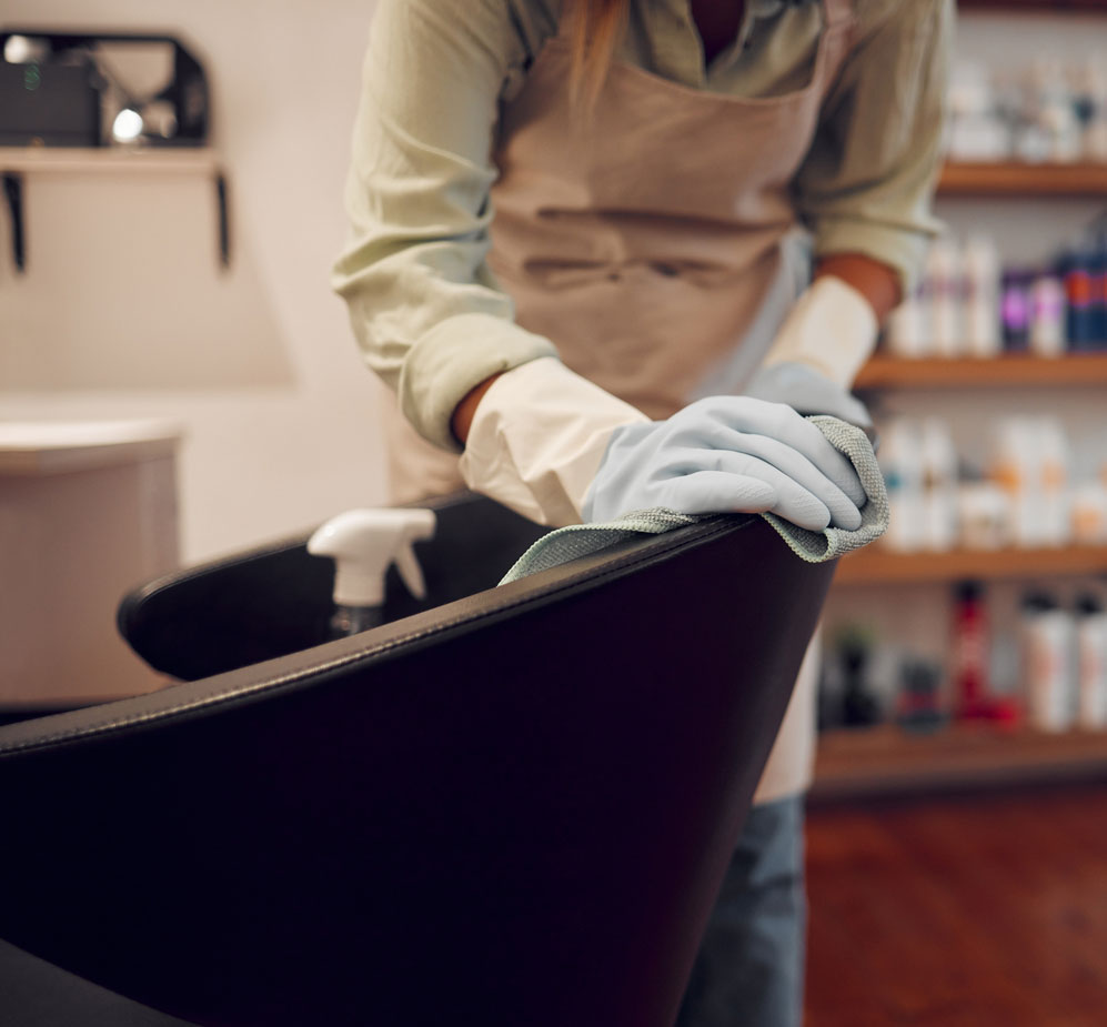 Trabajadora de la limpieza limpiando un sillón de peluquería de cuero